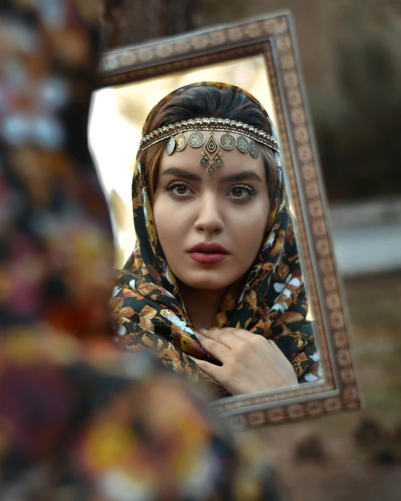 a woman wearing a head covering poses in front of a mirror