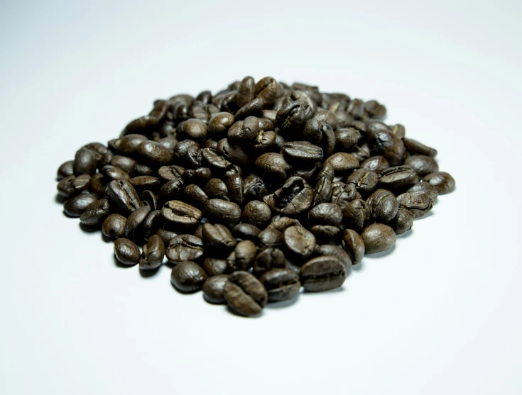 many roasted coffee beans are seen on this white surface