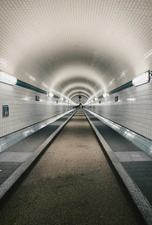 an empty subway station with a bench next to it