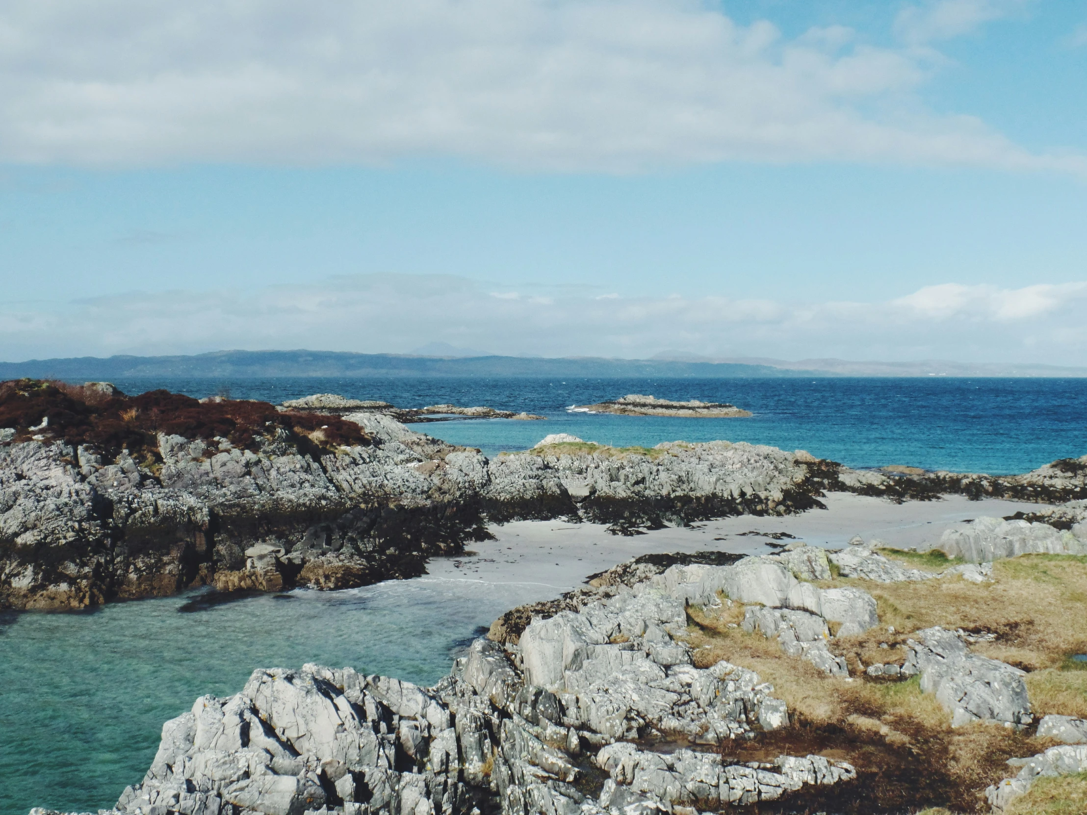 a rocky coastline is near a blue ocean