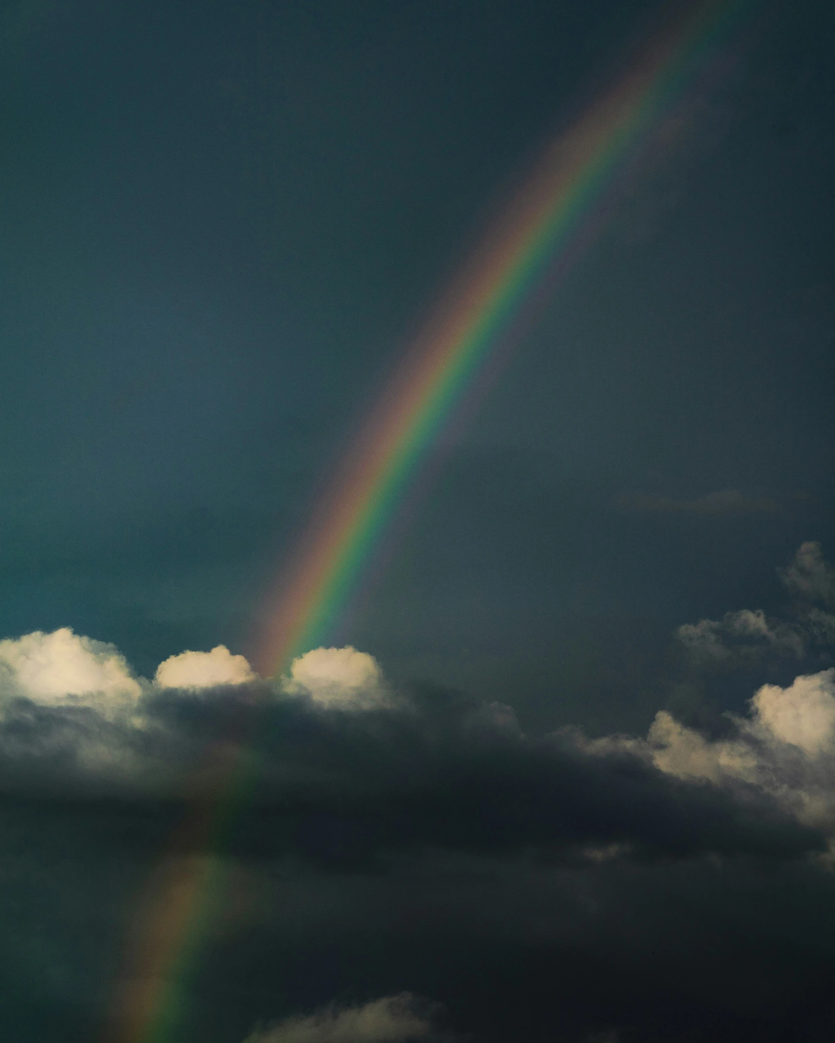 a very pretty rainbow in the sky with clouds