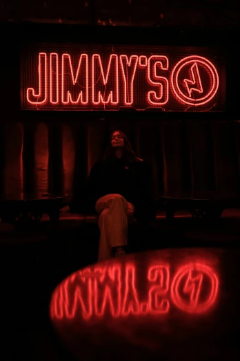a woman sitting on a bench under the jimmys atlanta sign