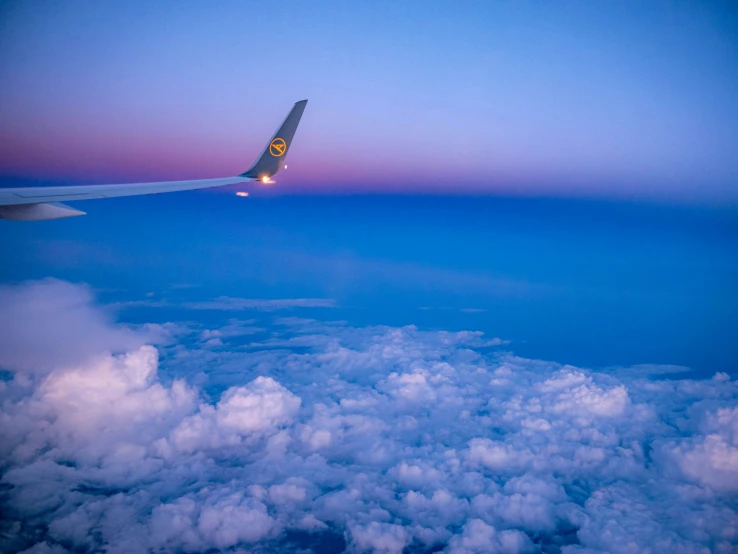 an airplane flying above clouds at dusk