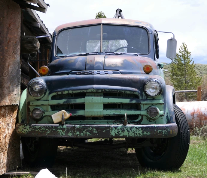 an old car is seen parked beside a rusty building