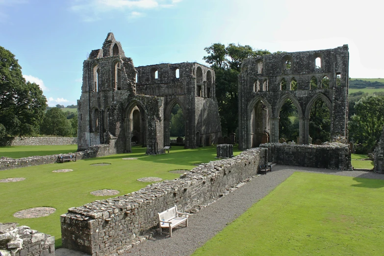 a stone building with multiple pillars next to a field