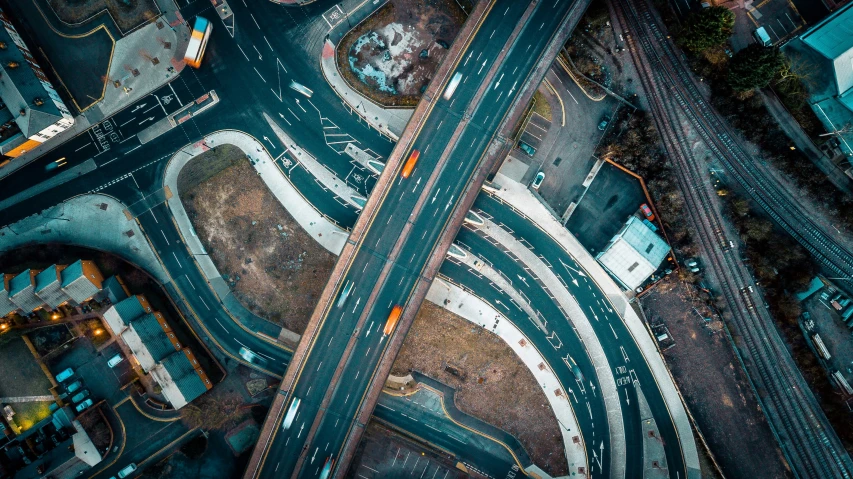 aerial view of intersection with cars on one side and an empty street, with multiple tracks leading to different stations