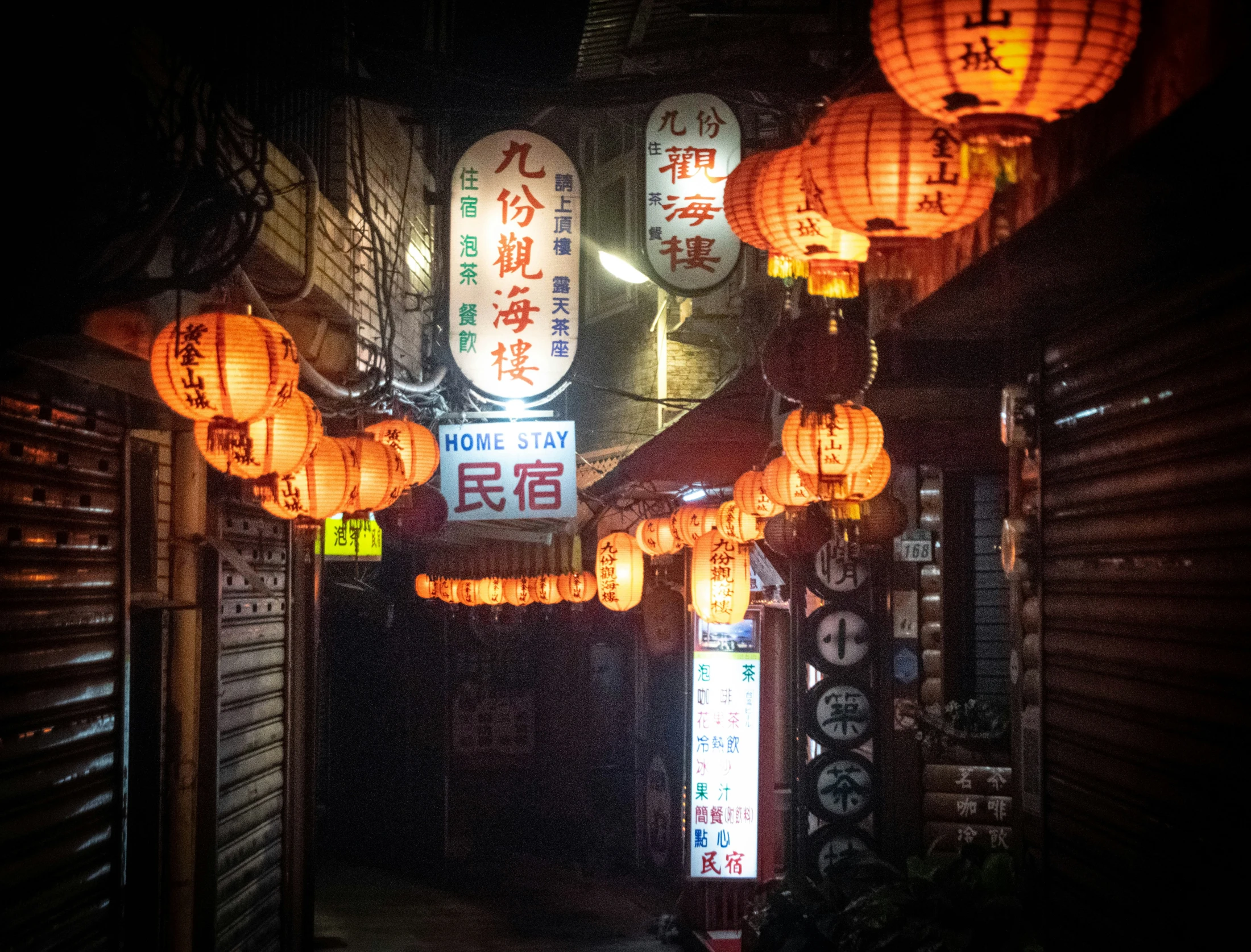 many lanterns are hanging over a dark alley