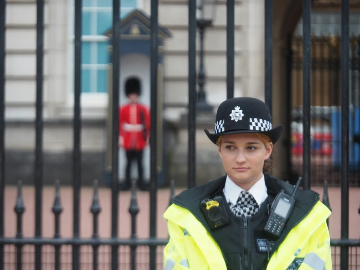 an attractive woman dressed in police clothes next to a metal fence