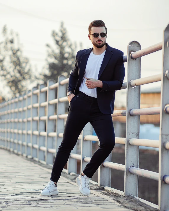 a man standing on the edge of a walkway in front of a metal fence