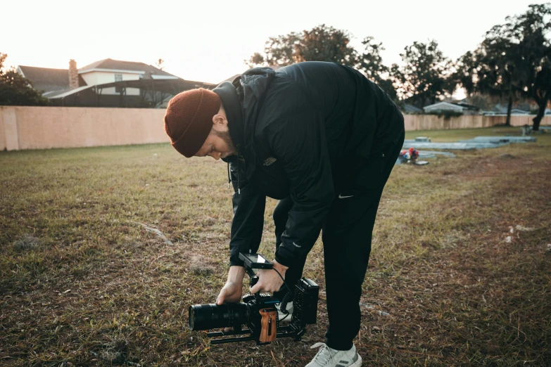 a man with a red cap and glove working on a power tool in a yard