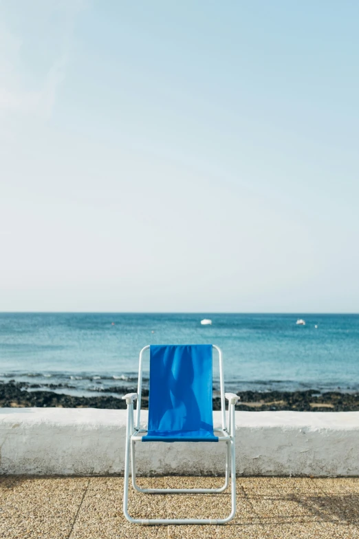 a chair is on the sidewalk near a beach