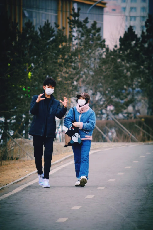 two people are walking down the street with masks on