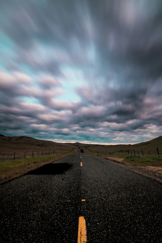 a lonely road with a yellow guardrail in the middle