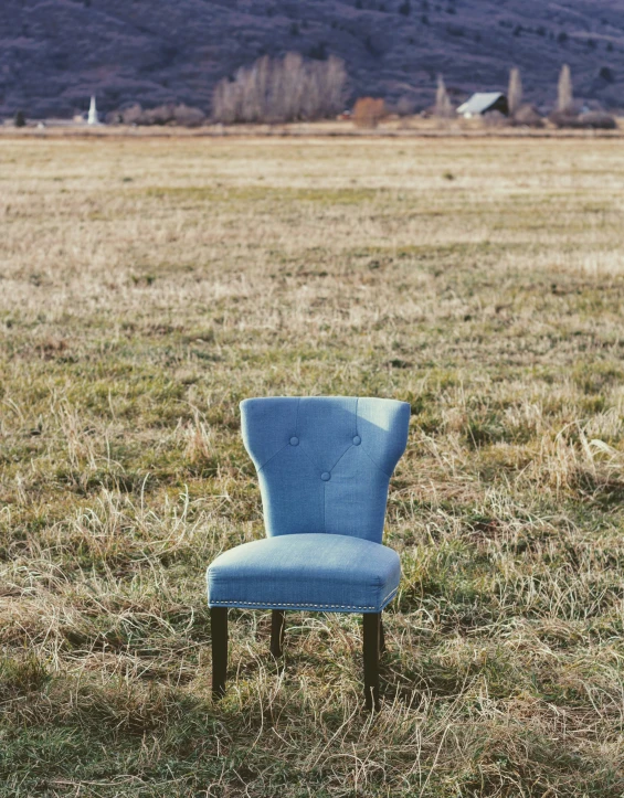 an old chair is in the middle of a large field