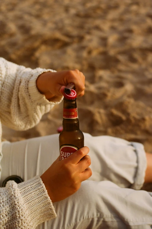 a man sitting on the beach holding up a beer