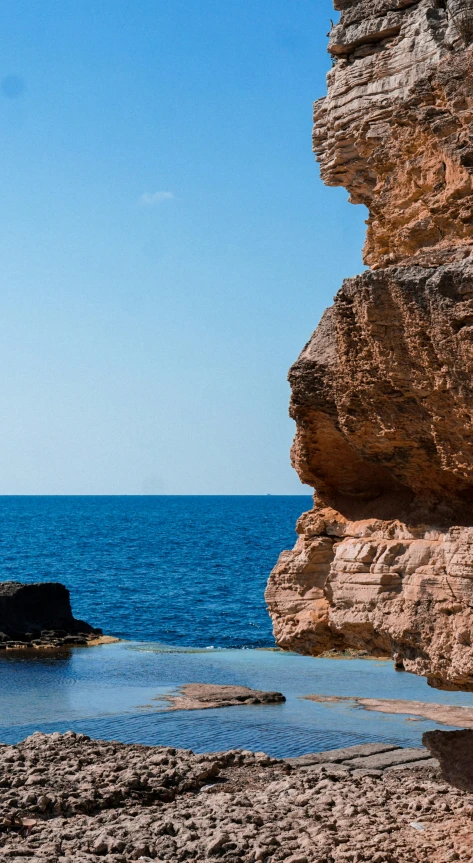 two people sitting on rocks near the ocean