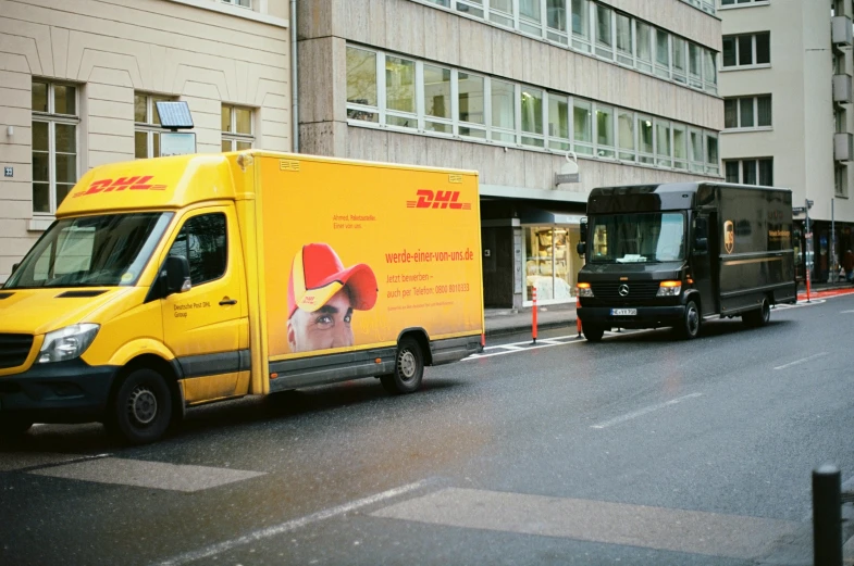 two trucks driving on a street near buildings