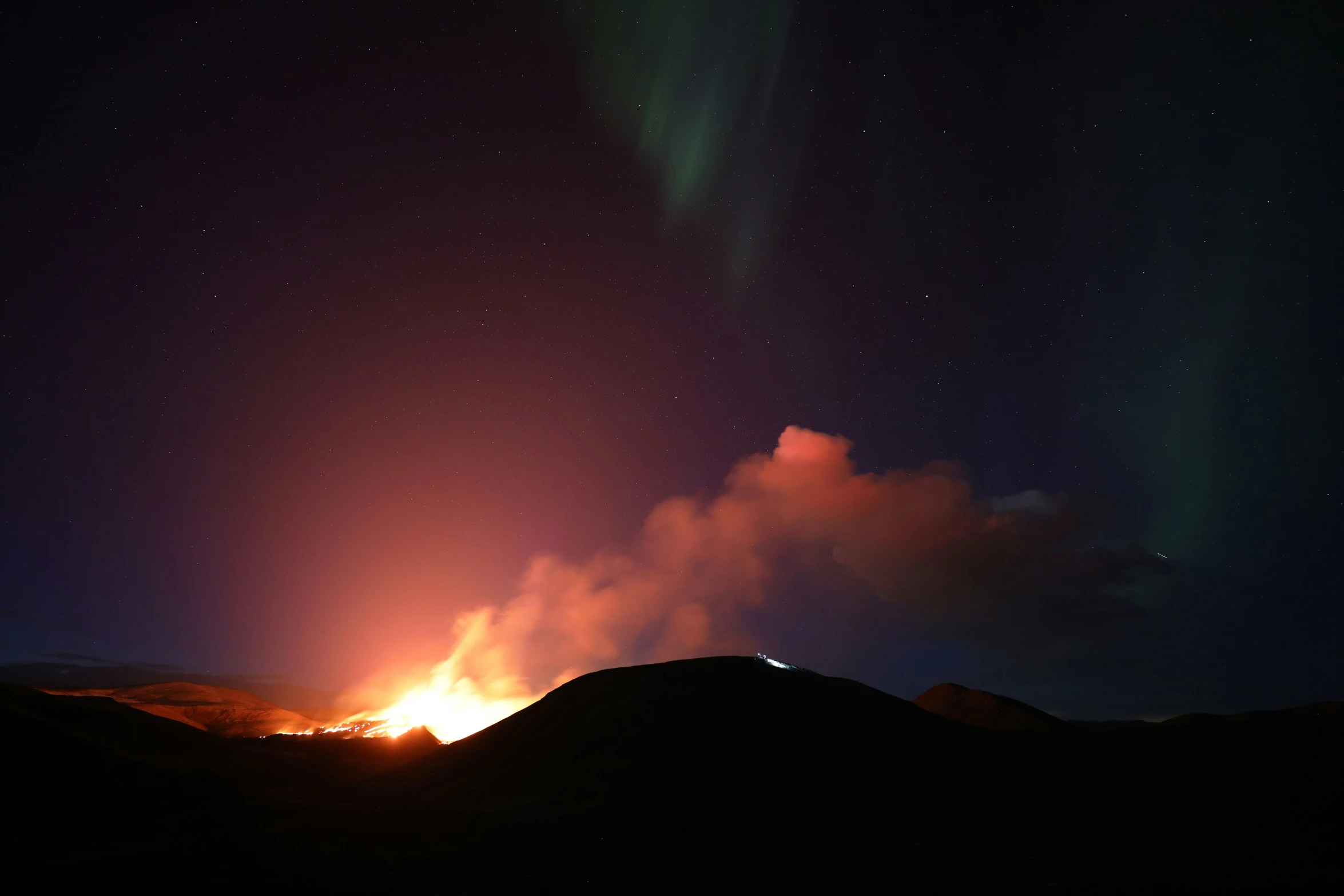 a hill covered in dark mountains under stars