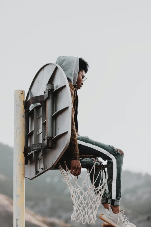 man with hood on standing on basketball net in outdoors