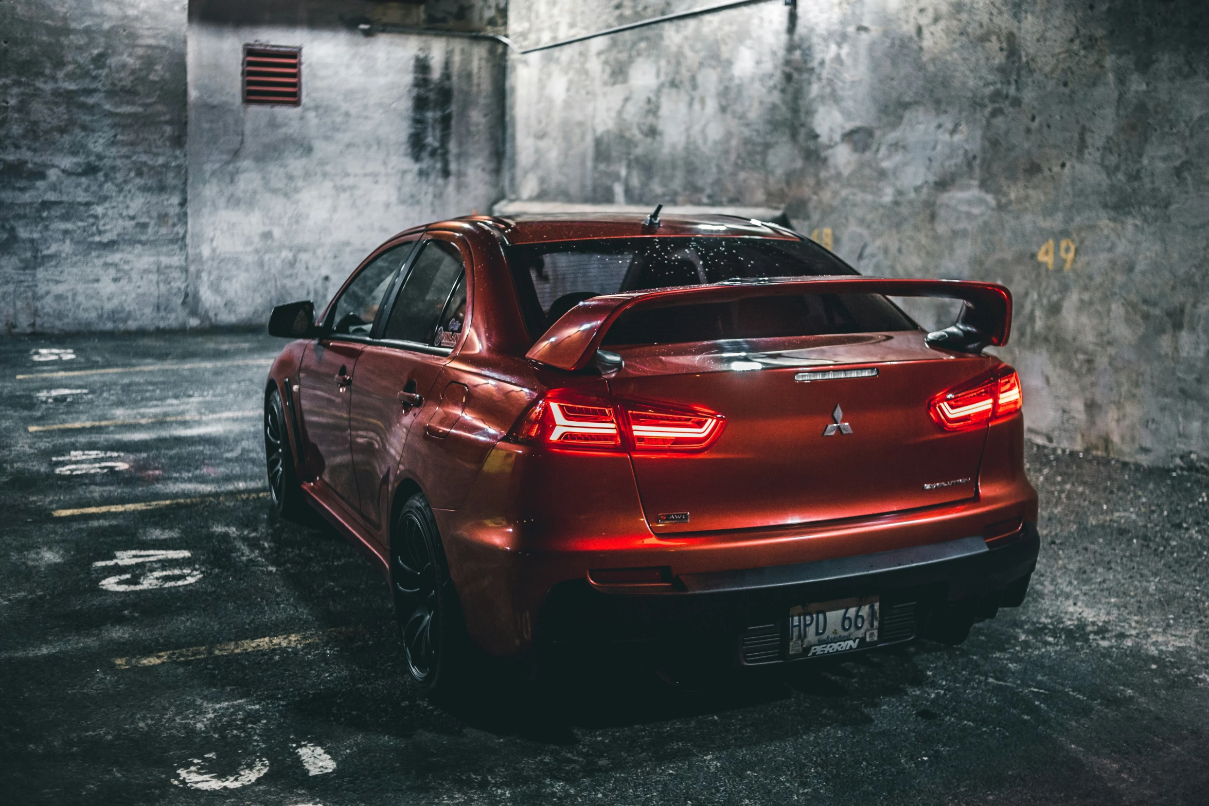 a red hatchback car parked in the middle of a dark space