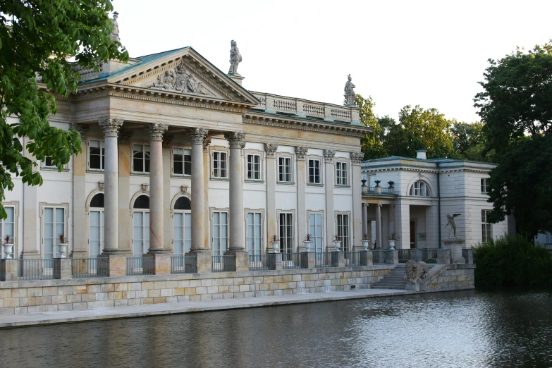 a large building with white columns and pillars near a body of water