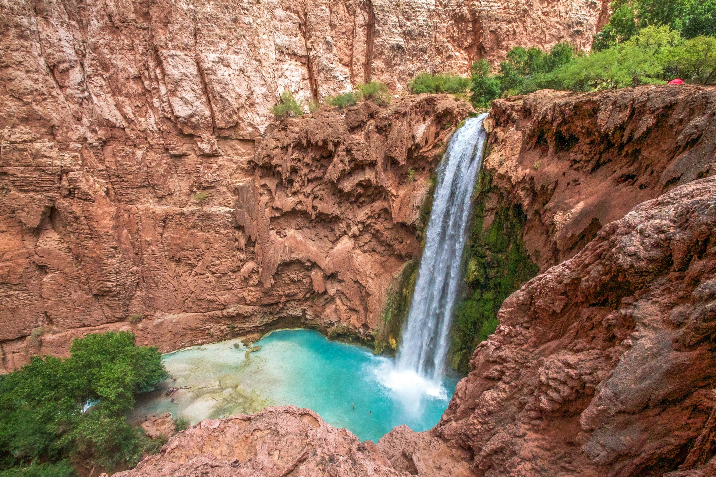 waterfall flowing over a narrow pool of water at the end of a cliff