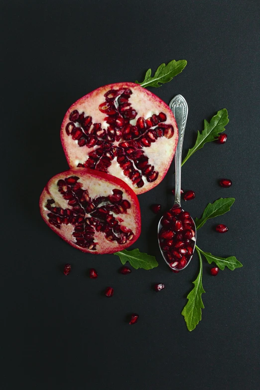 pomegranate on black with spoon in background