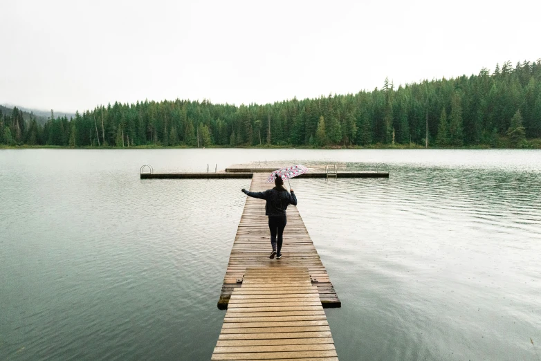 a man standing on a long dock with an umbrella