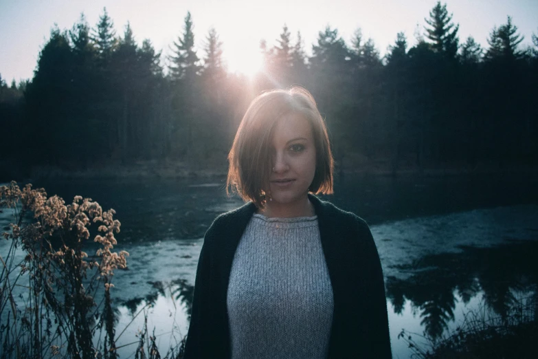 a woman posing for a picture with the sun setting behind her