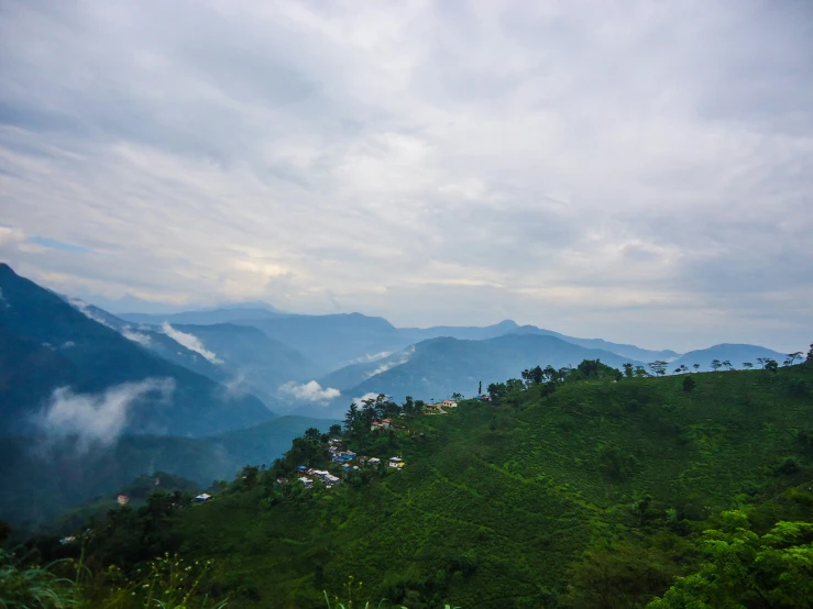 a hill surrounded by forest with fog in the sky