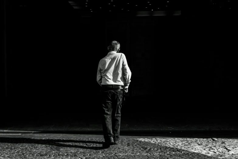 man standing by a dark building alone looking back