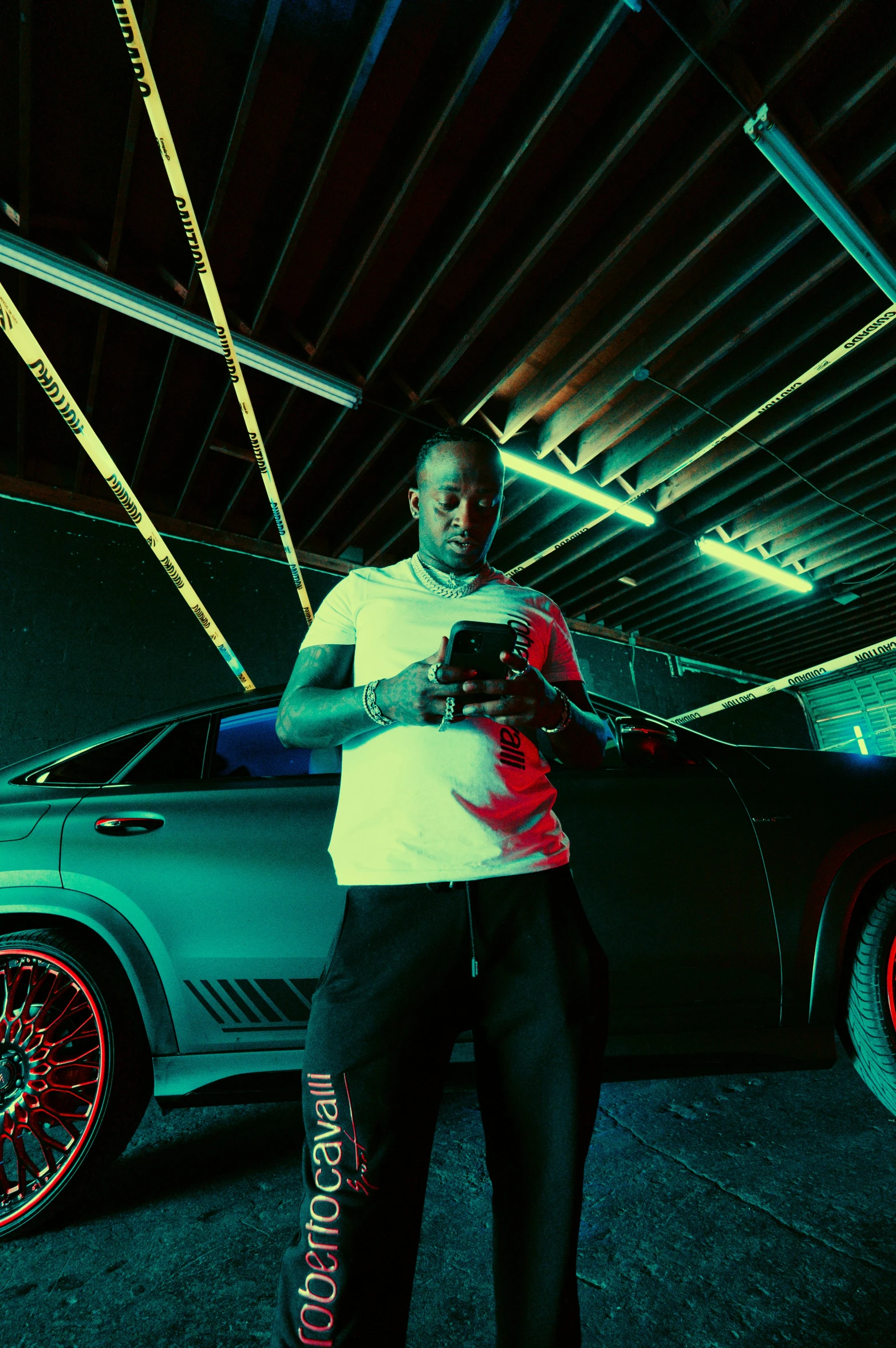 a man is holding his cell phone next to a parked car