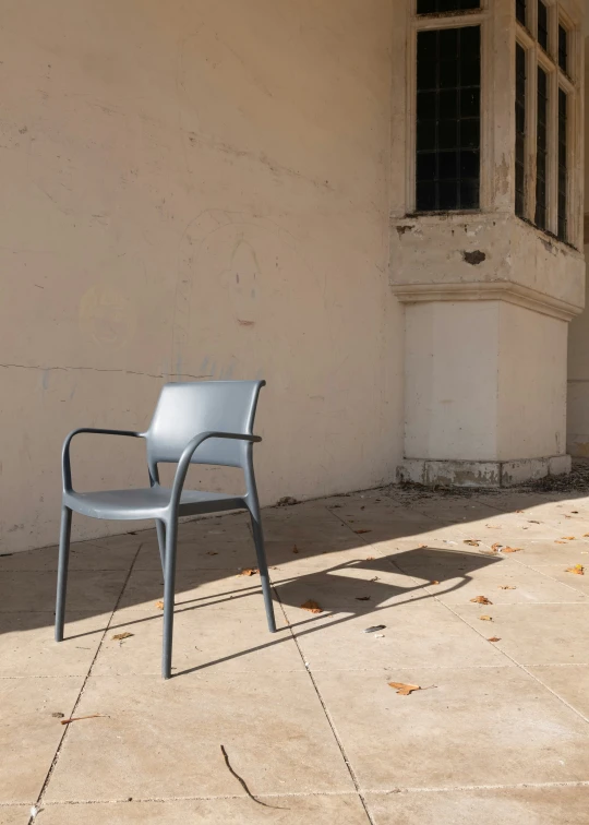 a chair sitting on concrete in front of an abandoned building