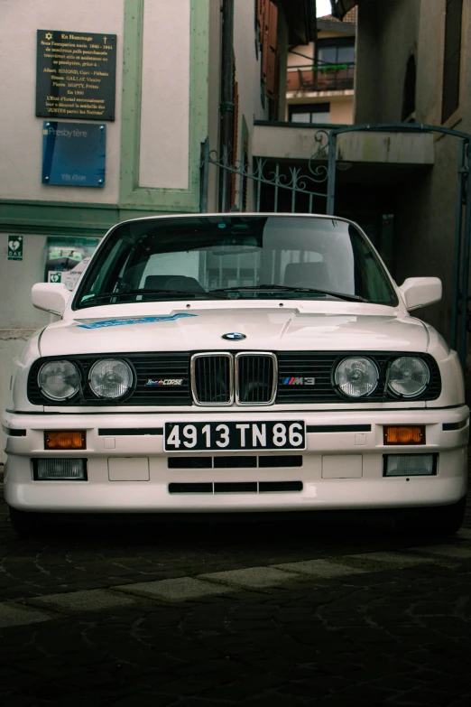 a white bmw parked outside a building in front of it's car door