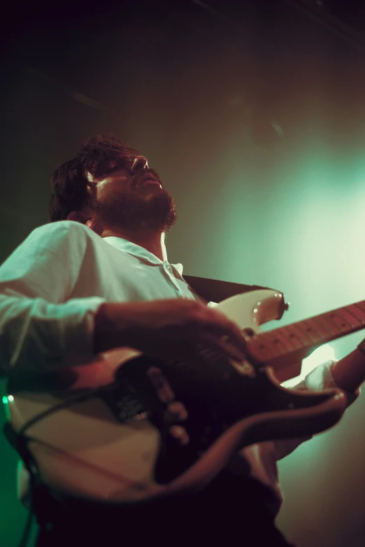 man playing on a guitar while wearing glasses