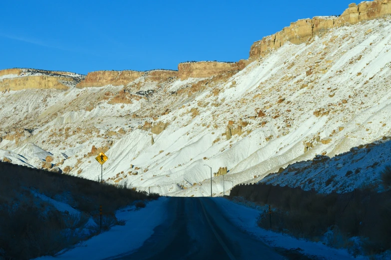 a road running by some mountain side covered in snow