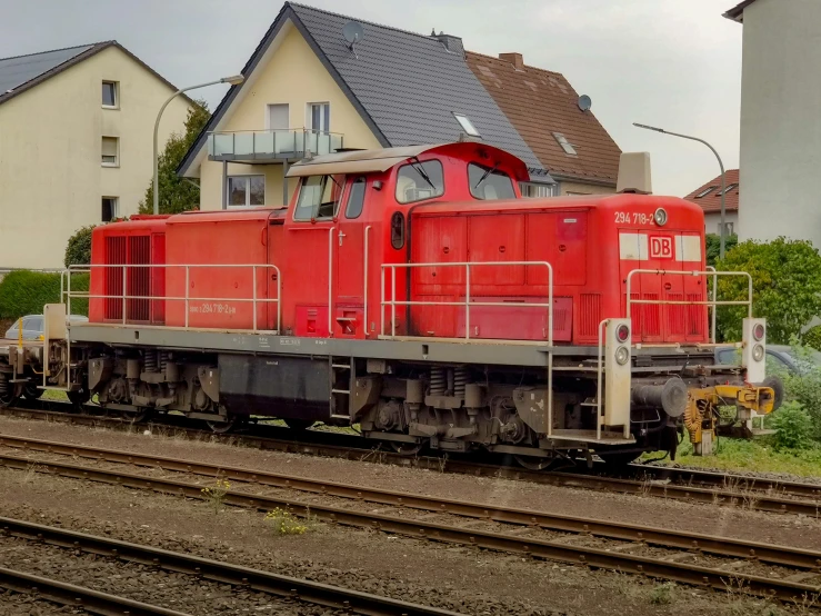 the train cart is parked on the tracks by the houses