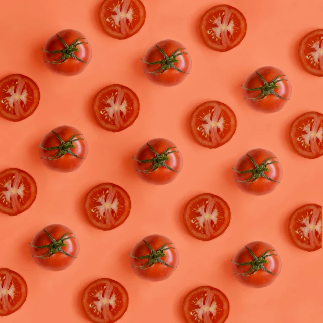 several tomatoes arranged on an orange background