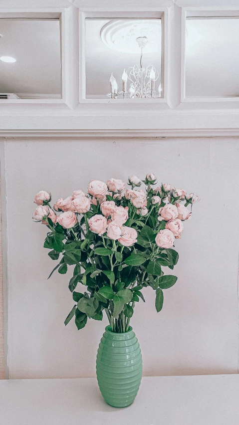 pink flowers sit in a green vase on the table