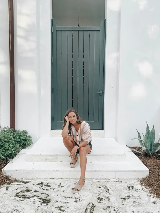 a woman is sitting on the steps outside of a white building