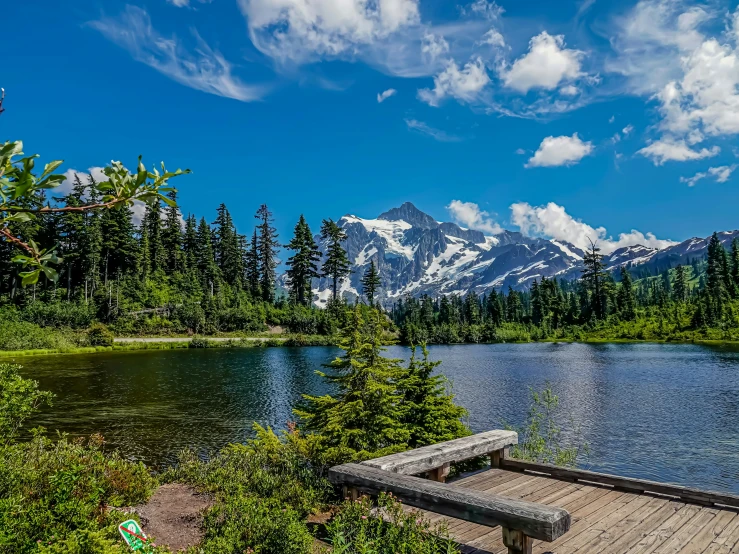 a bench sits on the edge of a pier near a lake