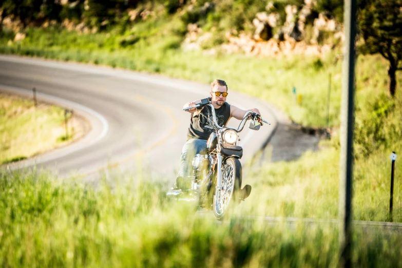 a man riding a motorcycle through a lush green field