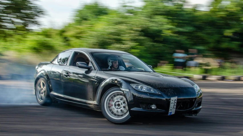 a black sports car is racing down the track