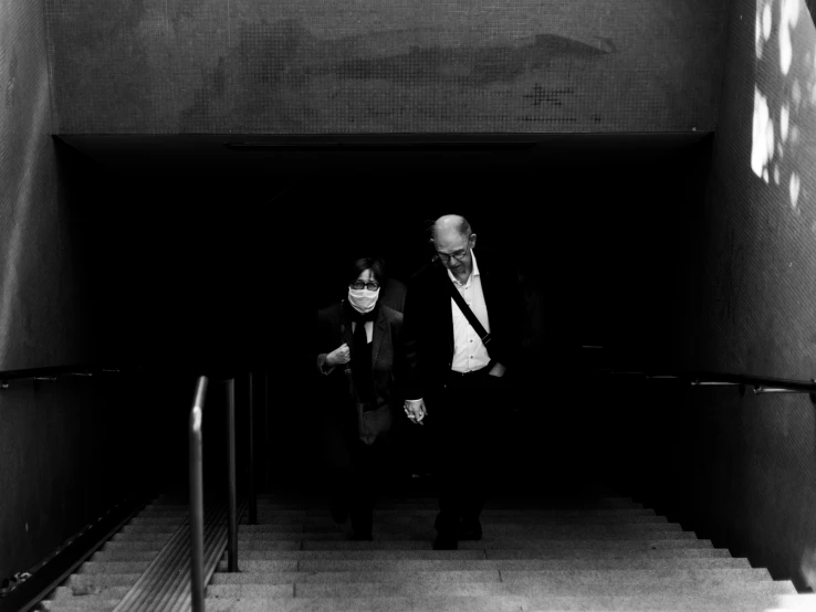 two men walk down the stairs wearing suits and ties