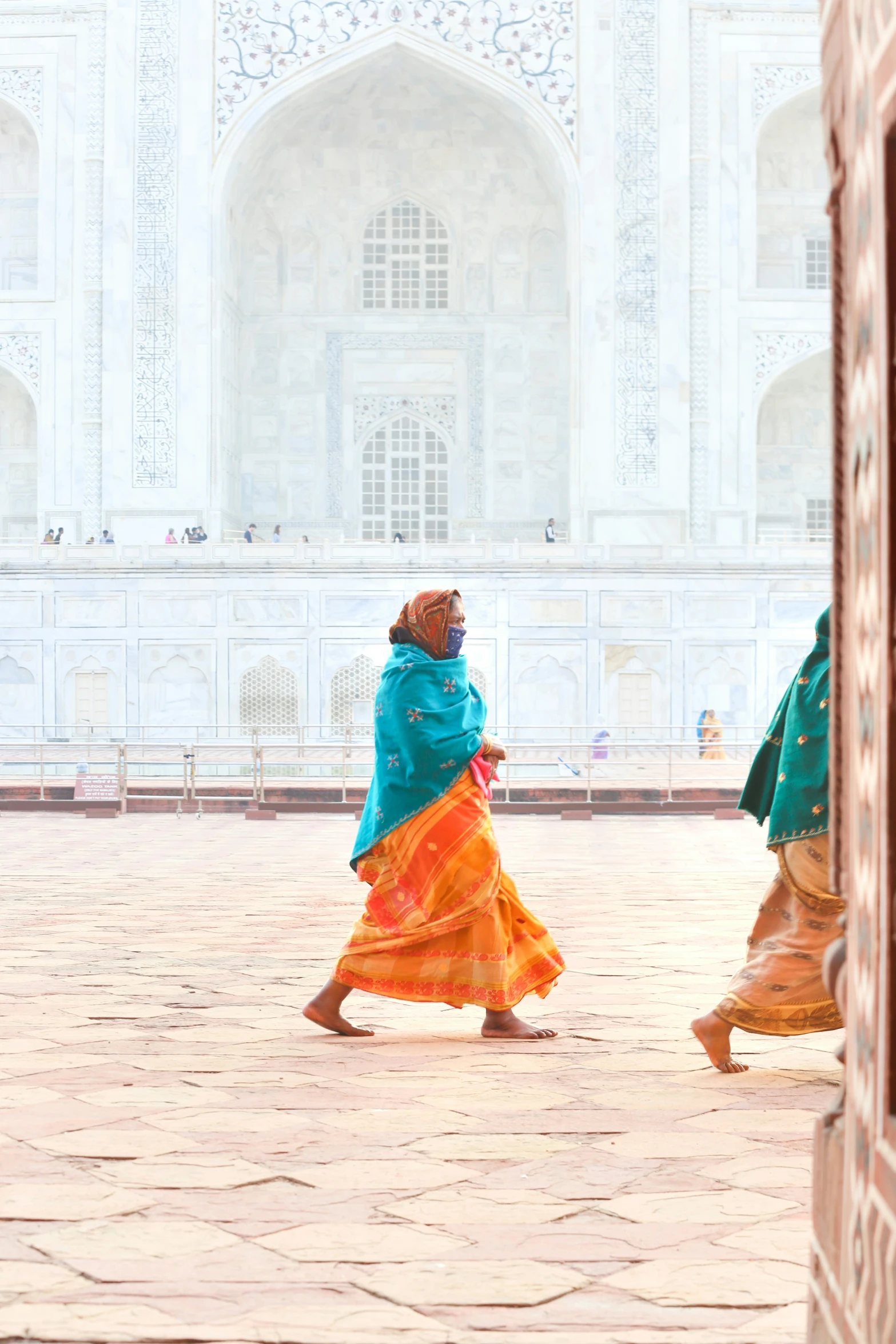 woman with blue jacket and orange dress walking in front of a building