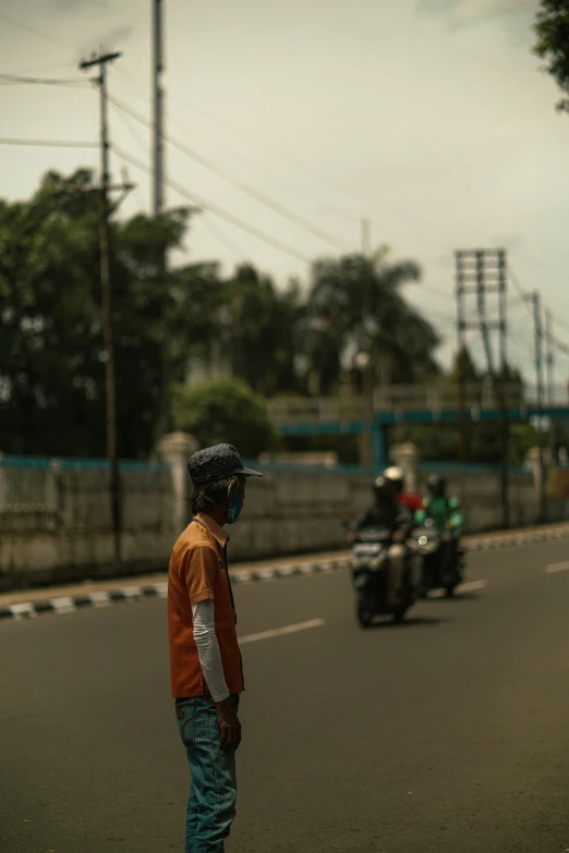 a man stands in the middle of a road with two motorcycles
