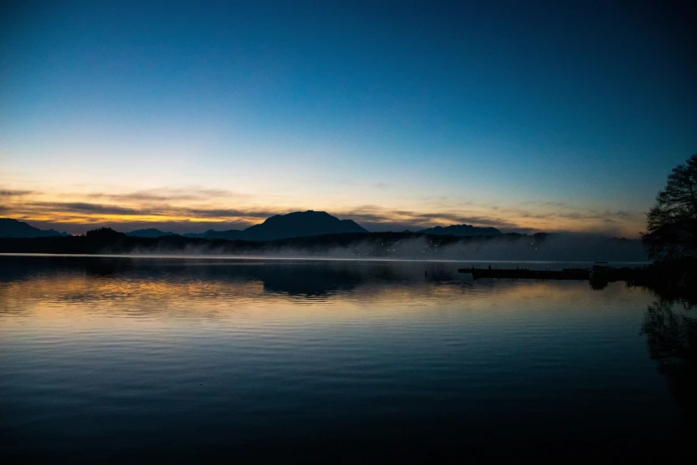 the mist covered water of a lake at dusk