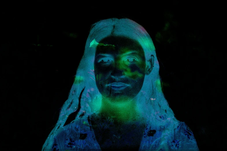 a woman covered in green light with her head turned to the side