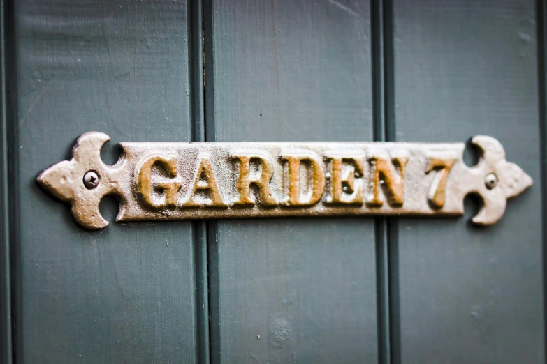 an antique metal garden 7 sign mounted to the side of a green door