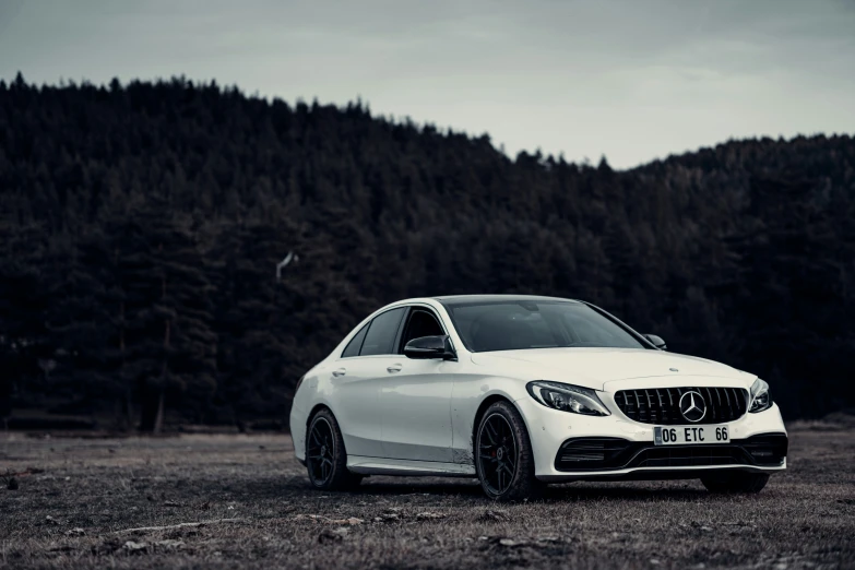 a white car parked in the middle of a field near mountains